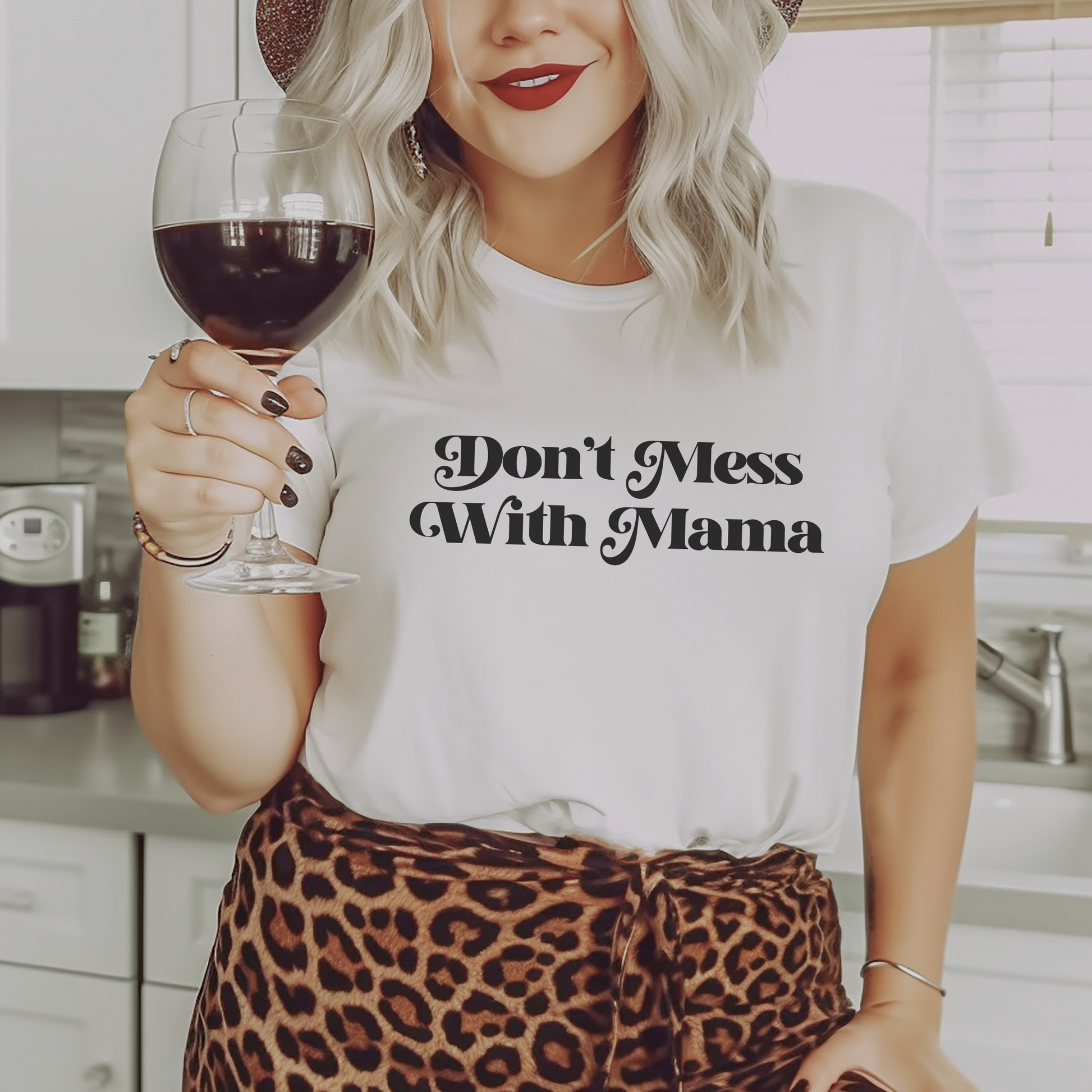 Blonde woman holding a glass of red wine wearing white “Don’t Mess With Mama” T-shirt. Mother’s Day Gift!