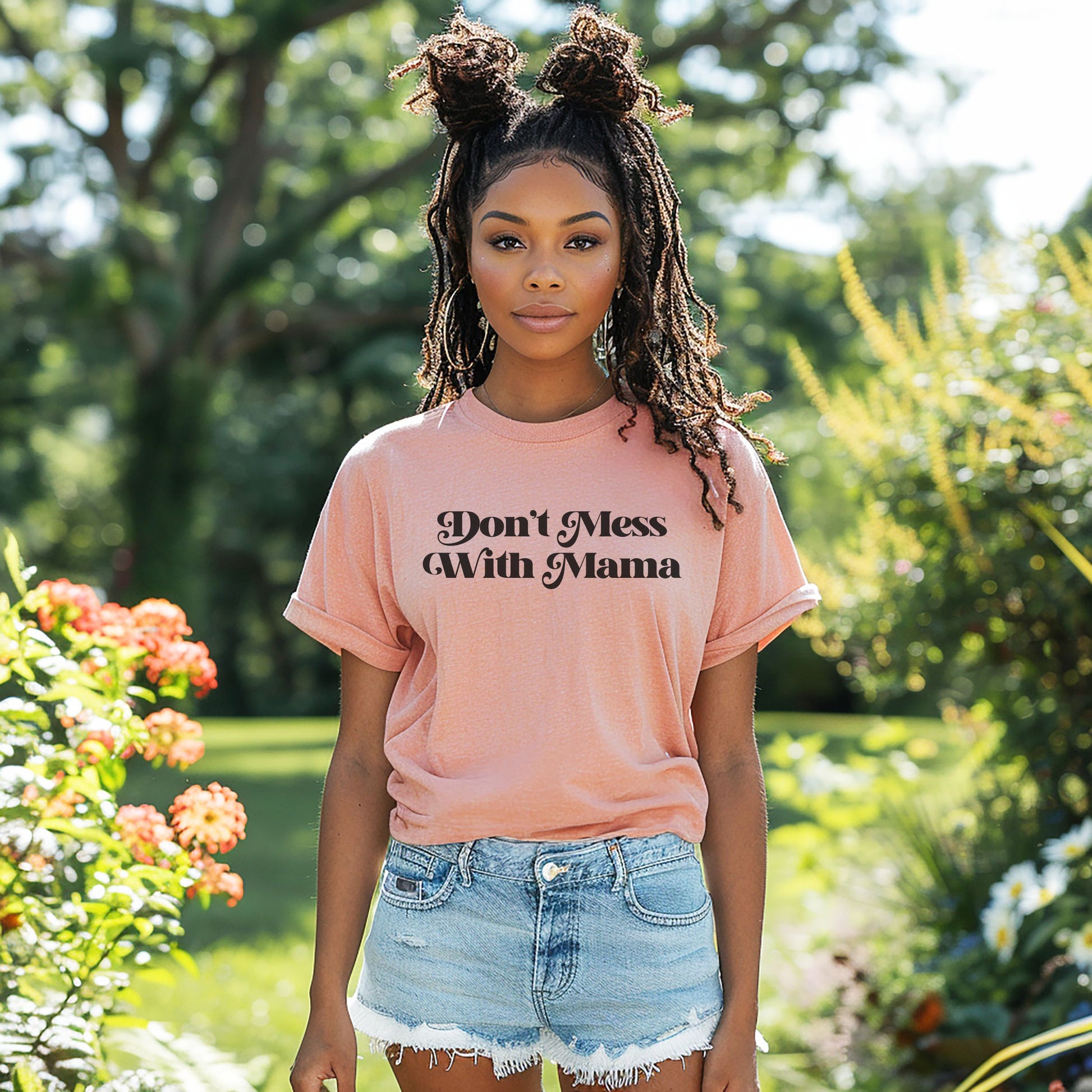 Black woman standing in a garden wearing heather peach colored “Don’t Mess With Mama” T-shirt. Mother’s Day Gift!